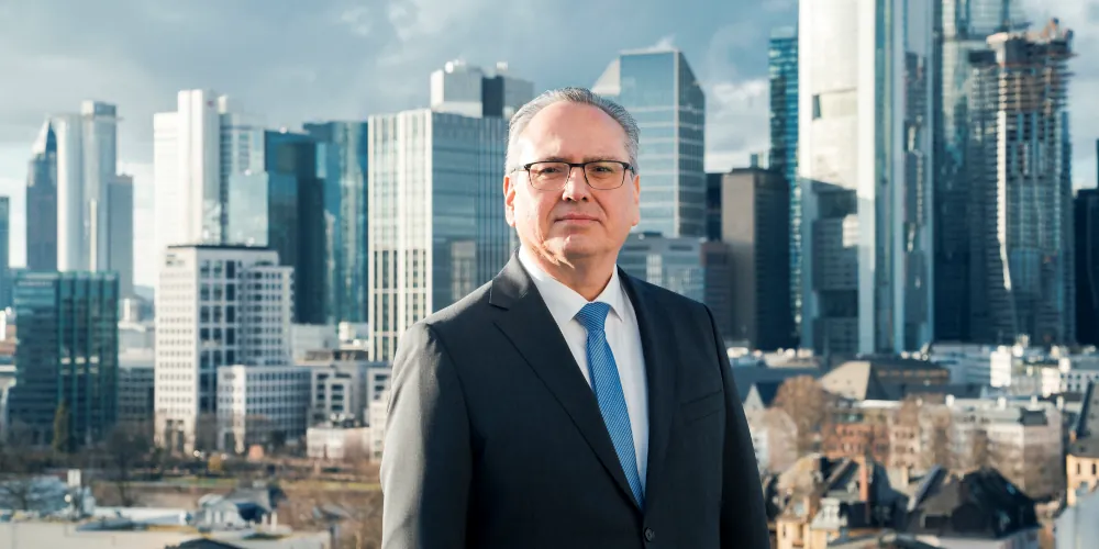 Der Fachanwalt für Arbeitsrecht ist auf dem Dach seiner Kanzlei vor der Skyline von Frankfurt zu sehen.